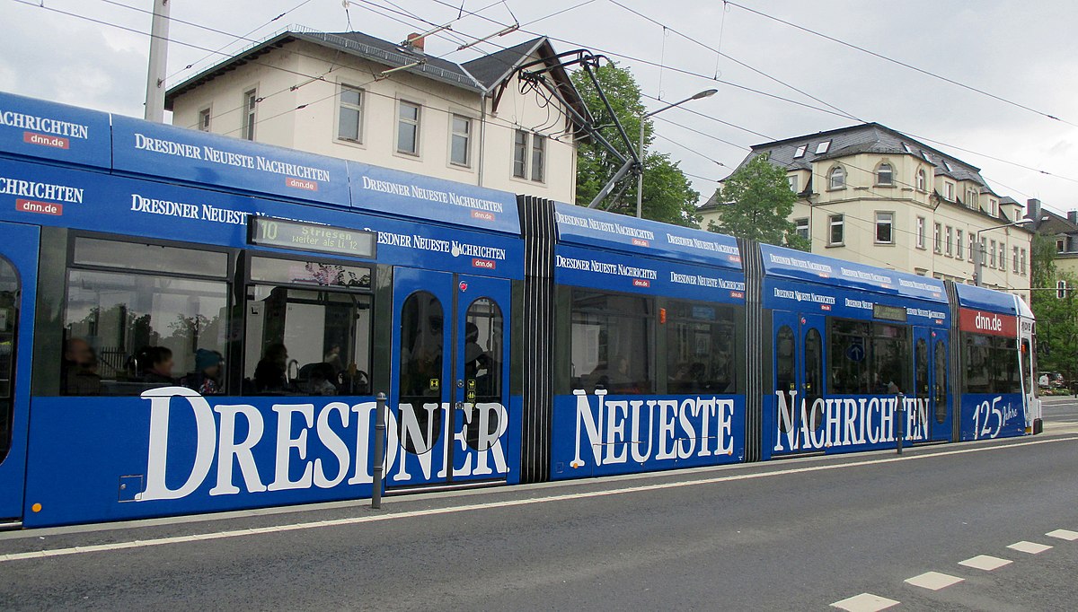 Blaue Straßenbahn mit Aufschrift Dresdner Neueste Nachrichten – 